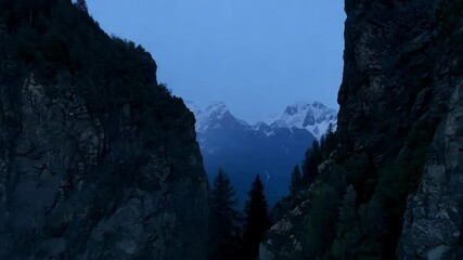 Aufkleber - The sun setting, snow capped mountains glow warmly, casting shadows over the valley. Transitioning from light to dark, creating a serene and majestic scene. Twilight sky in the background