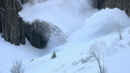 Aufkleber - Fresh powder snow is falling down a steep mountainside, blanketing the landscape in white. Trees and rocks are scattered across the mountain