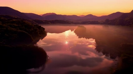 Poster - Beautiful landscape of a mountain lake with the rising sun reflecting on the water surface, creating a magical atmosphere with warm colors