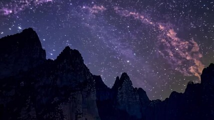 Aufkleber - The milky way galaxy is shining brightly in the night sky, illuminating the peaks of a mountain range below. The stars are twinkling and the milky way is a beautiful swirl of pink and white