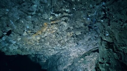 Poster - Beam of light illuminates the rocky ceiling of an underwater cave, revealing the rough texture and intricate details of the geological formations