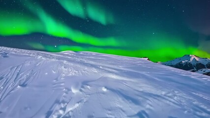 Poster - Green northern lights dancing over a snow covered mountain with ski tracks, creating a magical winter wonderland atmosphere