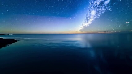 Poster - The calm ocean water meets the coastline under a starry sky, capturing the beauty of nature at night. The blue waters and dark horizon create a stunning contrast, making it perfect for backgrounds