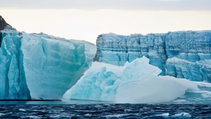 Aufkleber - Majestic icebergs are floating on dark blue water, their surfaces shining with vivid blue colors, creating a breathtaking spectacle of nature's beauty and power