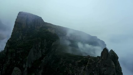 Poster - Misty mountain peaks shrouded in fog create a dramatic atmosphere in the wild landscape, with gray clouds adding to the gloomy ambiance