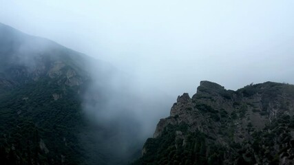 Aufkleber - Dense fog is rolling through a mountain valley, creating an eerie and mysterious atmosphere as the peaks are shrouded in mist