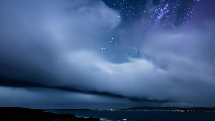 Wall Mural - massive dark cloud formation is hovering over a city skyline by the sea, with lights illuminating fr