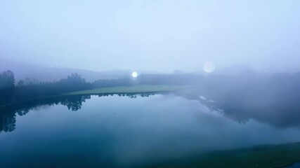 Aufkleber - Morning mist is rising from a lake surrounded by a forest, creating a serene and peaceful atmosphere. The reflection of the trees in the water adds to the beauty of the scene