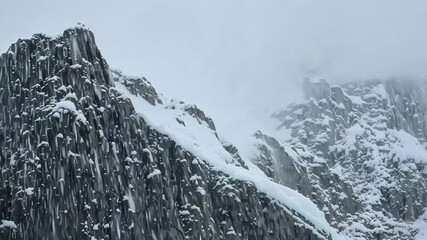 Aufkleber - Snow capped mountains rise above clouds on a cold, misty day, creating a winter landscape. Rocky terrain covered in white snow, frosty blue sky