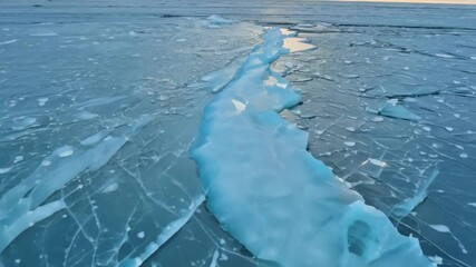 Aufkleber - The frozen lake surface displays turquoise and white ice formations with intricate cracks, creating a mesmerizing natural design