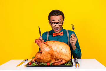 Canvas Print - Photo of amazed guy sit table with raised cutlery excited eating thanksgiving day big turkey isolated bright color background