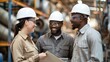 © BrightWhite - Three factory workers, diverse colleagues, black male and female, discussing new technology applications, reviewing project documents, collaborating on innovative solutions in industrial setting