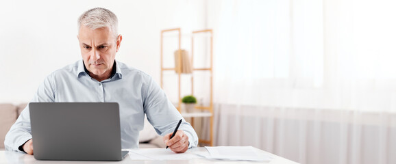 Budget Planning. Pensive Senior Man Using Laptop And Writing In Notebook Sitting At Desk At Home, Empty Space