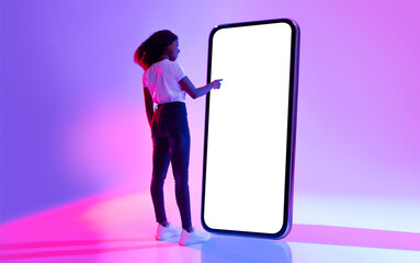 Poster - Full length of young black woman touching screen of giant smartphone in neon light, mockup for new mobile app or website design. African American lady interacting with big cellphone, space for ad