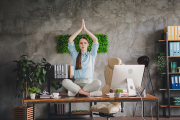 Photo of adorable positive lady broker wear shirt eyeglasses sitting table rising hands practicing yoga indoors workplace workshop