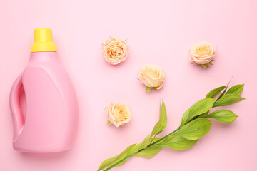 Wall Mural - Bottle of laundry detergent, green branch and flowers on pink background, closeup