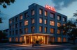 © InfiniteStudio - Modern hotel exterior illuminated at dusk with glowing sign and inviting entrance in a quiet neighborhood