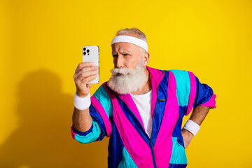 Wall Mural - Photo of handsome uncertain senior guy oldschool sportswear reading modern gadget emtpy space isolated yellow color background