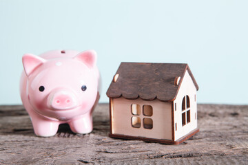 Wall Mural - miniature piggy bank and miniature houses on wooden background