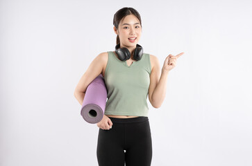 Wall Mural - Portrait of young Asian girl wearing sports clothes, headphones and posing on white background