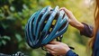 © เลิศลักษณ์ ทิพชัย - A detailed shot of a person hand adjusting a bicycle helmet strap, with a bike and green trees in the background, emphasizing eco-friendly transportation.