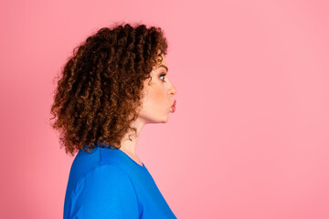 Wall Mural - Side profile of young woman in casual sweatshirt pouting against vibrant pink background