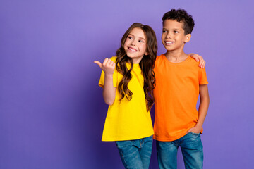 Photo of lovely two little kids hugging point empty space dressed stylish orange yellow garment isolated on purple color background