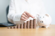 © Jo Panuwat D - Money Saving for Future Plan, Retirement fund, Pension, Investment, Wealth Business and Financial concepts. Woman Counting and calculate money with coins stack with piggy bank for deposit