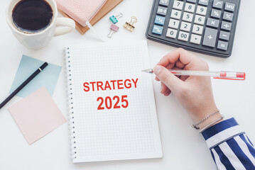 A person writes a strategy plan for 2025 using a notebook