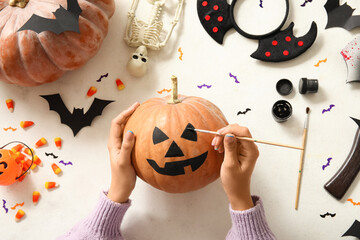 Wall Mural - Woman painting Halloween pumpkin at white table