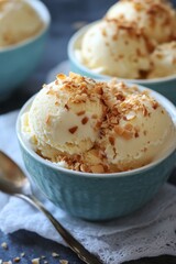 Close-up of vanilla ice cream scoops topped with chopped almonds in blue bowls.