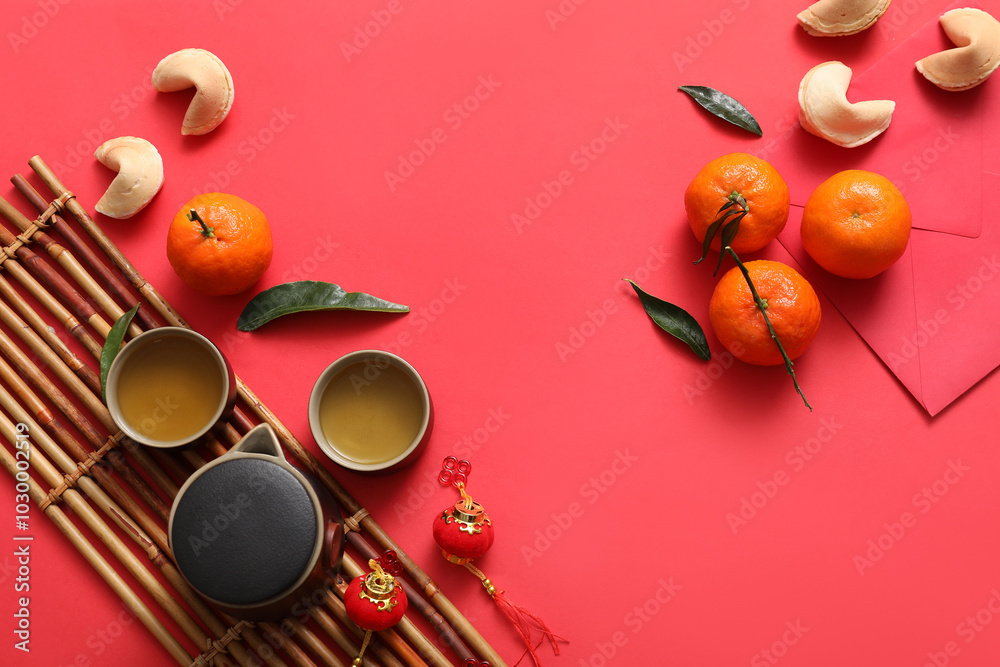 Composition with bamboo mat, tea set, tangerines and Chinese symbols on red background. New Year celebration