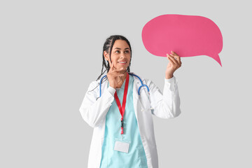 Young African-American female doctor with stethoscope and speech bubble on white background