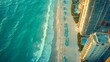 © Lifia - Aerial view of a beach with turquoise water and tall city buildings nearby