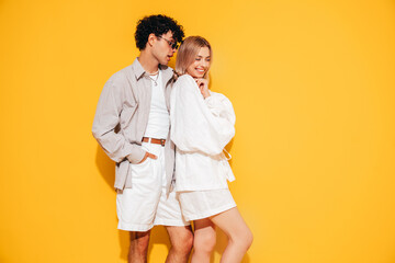 Canvas Print - Happy beautiful romantic teenage couple. Smiling handsome caucasian man and young woman in summer clothes posing in studio, hugging sharing emotions, cheerful and happy. Isolated on yellow, sunglasses