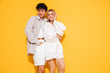 Canvas Print - Happy beautiful romantic teenage couple. Smiling handsome caucasian man and young woman in summer clothes posing in studio, hugging sharing emotions, cheerful and happy. Isolated on yellow