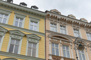 There is a bright yellow building situated right next to another structure that has white windows adorning its facade, creating a lovely contrast