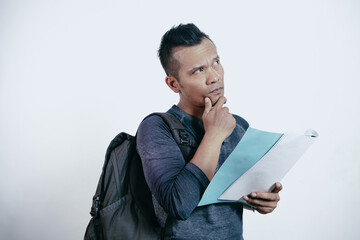 Wall Mural - Asian man student showing thinking gesture with his eyes looking up holding document paper.