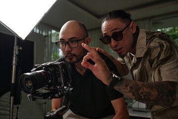 Director controlling the work of cameraman while he making shots on his camera in studio