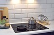 © Natalia - The frying pan and saucepan are on a modern induction hob. The area around the hob is illuminated by lamps from the hood.