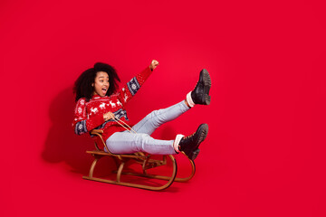 Poster - Full length photo of adorable lovely girl wear ugly ornament sweater riding sledges celebrating noel xmas empty space isolated red color background