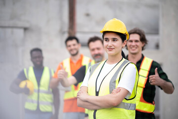 Young White engineer woman cross arm at chest looking front visually with smile at work site. Portrait of engineer wearing white hard hat with blur smile of teamwork.