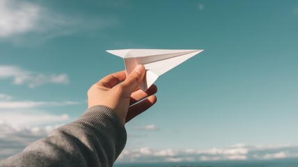 A hand launching a white paper airplane into a cloudy blue sky representing the concepts of adventure freedom creativity innovation and the endless possibilities for growth success