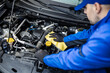 © zphoto83 - Technician inspects and cleans engine components inside a vehicle at an automotive workshop during daylight hours