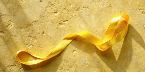 Wall Mural - Yellow ribbon elegantly curled on a textured golden background.