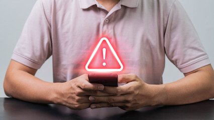 Fototapete - Mobile Security Alert, A Man Using a Smartphone with a Scam Warning Symbol to Highlight the Growing Threat of Mobile Fraud and Cyber Scams in the Digital Age.