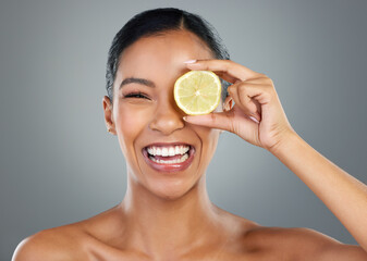 Poster - Happy woman, portrait and lemon with vitamin C for skincare, beauty or natural cosmetics on a gray studio background. Young, female person or model with smile for organic citrus fruit or antioxidant