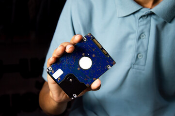Fototapete - A male technician holds a 2.5-inch hard drive, a data storage device.
