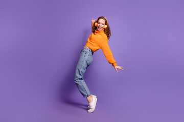 Wall Mural - Full size photo of nice young girl stand tiptoe headphones wear pullover isolated on violet color background