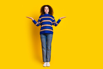 Wall Mural - Full size photo of positive woman dressed striped sweater palms comparing products empty space isolated on yellow color background